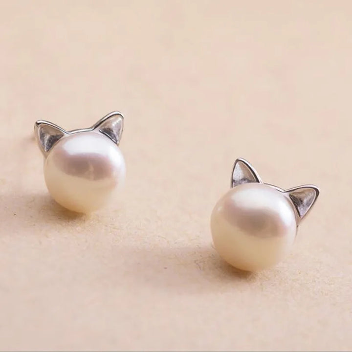 "Pendientes de Gato en Plata Esterlina con Perlas" puede reescribirse como "Pendientes de Stud de Gato de Plata con Perlas".